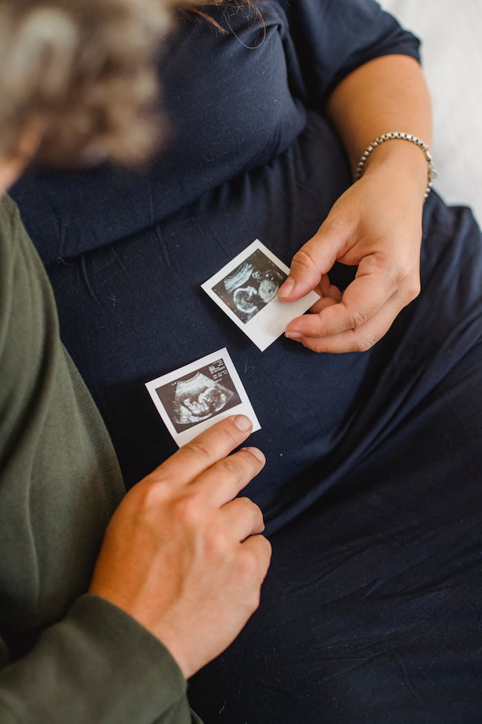 A pregnant couple holding ultrasound images, symbolizing anticipation and parenthood.